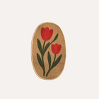 Oval-shaped woven mat with red tulip design on a beige background