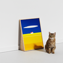 Cat sitting next to HÄDDEN landscape art scratcher. Wooden standing board that adds a dreamy, artistic touch to apartment decor